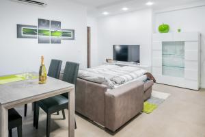 uma sala de estar com um sofá, uma mesa e uma televisão em Fior Apartments Schiller em Merano