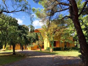 a yellow building with trees in the foreground at Tenuta de Paoli in Castellina Marittima