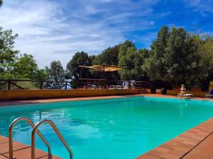 a swimming pool with a woman sitting in a chair next to it at Tenuta de Paoli in Castellina Marittima