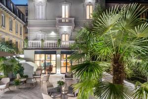 a lobby with tables and palm trees in front of a building at Magville in Milan