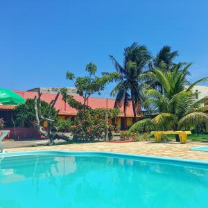 a swimming pool in front of a resort with palm trees at Pousada dos Gravatais in Marataizes