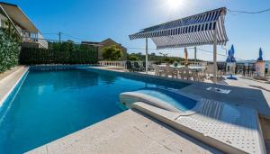 a swimming pool with a lounge chair and an umbrella at Villa Arka in Cavtat +26 photos
