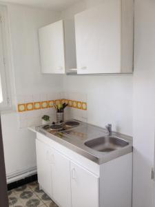 a kitchen with a sink and white cabinets at Ma Location Saisonnière in Chasseneuil-du-Poitou