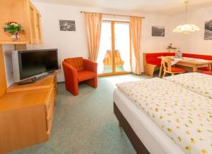um quarto de hotel com uma cama e uma televisão de ecrã plano em Gästehaus Schmid em Obermaiselstein