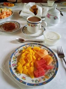 a table with a plate of fruit and a cup of coffee at Copper Canyon Riverside Lodge in Batopilas