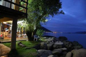 uma casa com vista para a água à noite em Prainha da Nina Apartamentos em Florianópolis mais 18 fotografias