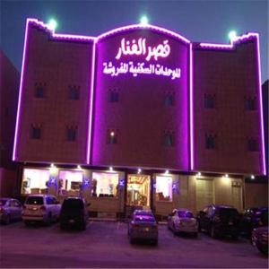 a lit up building with cars parked in a parking lot at Al Fanar Palace 1 in Riyadh