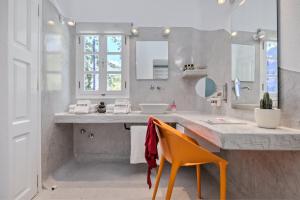 a bathroom with a sink and a orange chair at Kouros Village Hotel - Adults Only in Perissa