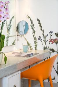 a desk with a mirror and a orange chair at Kouros Village Hotel - Adults Only in Perissa