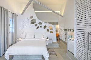 a white bedroom with a large bed and a hallway at Kouros Village Hotel - Adults Only in Perissa