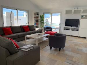a living room with a couch and a table and a tv at Villa Malagueñas in Puerto del Carmen