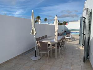 a patio with a table and chairs and an umbrella at Villa Malagueñas in Puerto del Carmen