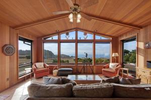 a living room with a ceiling fan and large windows at Sunset Point in Fort Bragg