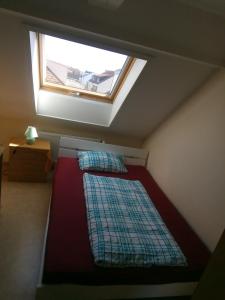HeddesheimにあるHotel Kalimeraのベッドと窓が備わる小さな屋根裏部屋です。