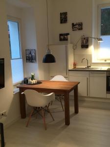 cocina con mesa de madera y 2 sillas blancas en Apart-ment 84 en Herdecke