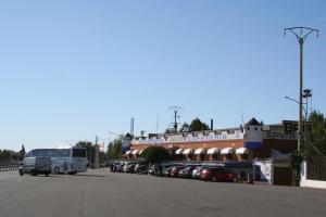 a bus driving past a parking lot with cars at Hostal Santa Ana in Madridejos