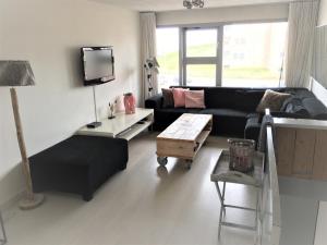 ein Wohnzimmer mit einem schwarzen Sofa und einem Tisch in der Unterkunft Beach House SEA-side in Egmond aan Zee