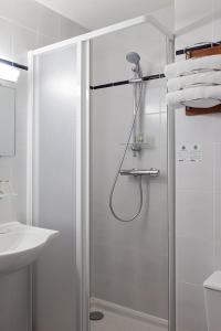 a shower with a glass door in a bathroom at Sky Hotel Goussainville Charles de Gaulle in Goussainville