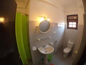 a bathroom with a sink and a mirror and a toilet at Seagreen Guesthouse in Galle