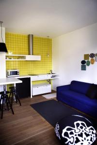 a living room with a blue couch and a kitchen at Mxp Rooms Guest House in Cardano al Campo