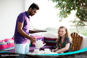 a man and a woman pouring a pot on a table at Seagreen Guesthouse in Galle