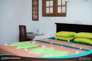 un letto con lenzuola verdi e cuscini gialli di Seagreen Guesthouse a Galle