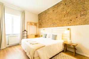 1 dormitorio con 1 cama grande y pared de piedra en Ericeira Soul Guesthouse, en Ericeira
