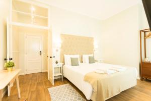 a white bedroom with a large bed and a table at Ericeira Soul Guesthouse in Ericeira