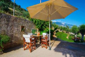 a table with chairs and an umbrella in front of a stone wall at St George's Castle House in Peratáta
