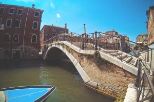 a bridge over a canal with a boat in the water at La Serenissima - 15 min to Venice City Center - Free Parking in Campalto