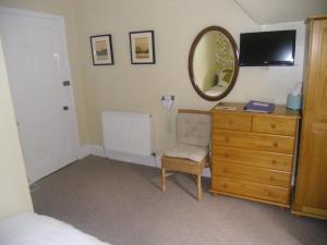 a bedroom with a dresser and a mirror and a chair at Ormidale Hotel in Brodick