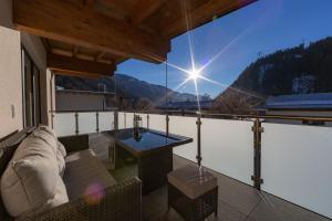 een balkon met een bank en een tafel op een dak bij Alpen Apart Heiss - DELUXE XL Apartments in Prutz