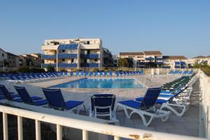 una fila de sillas y una piscina en el balcón en Agréable T2 balcon et piscine dans résidence bord de mer en Lacanau-Océan