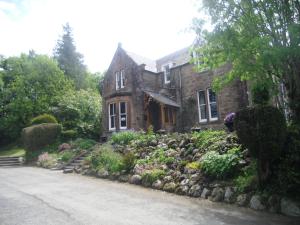 uma antiga casa de pedra com um jardim em frente em Ormidale Hotel em Brodick