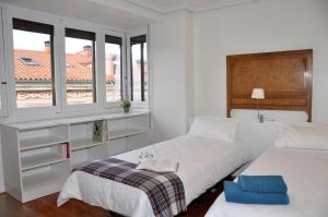 biała sypialnia z dwoma łóżkami i oknem w obiekcie VillaDel Casa Urbana w mieście Burgos