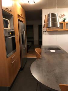 eine Küche mit einem Tisch und einem Kühlschrank aus Edelstahl in der Unterkunft Sæból/Ocean Lair 2 in Grundarfjörður