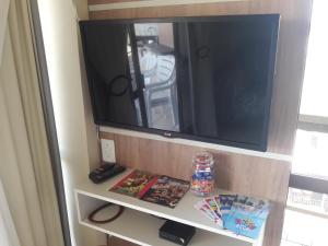 TV en un estante de una habitación en APTO 50M PRAIA NA AVENIDA - 6 PESSOAS, CHURRASQUEIRA, WIFI, SACADA, GARAGEM PARA VEICULOS PEQUENOS! - Residencial Roveda, en Bombinhas