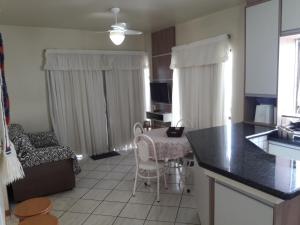 cocina y sala de estar con mesa y sillas en APTO 50M PRAIA NA AVENIDA - 6 PESSOAS, CHURRASQUEIRA, WIFI, SACADA, GARAGEM PARA VEICULOS PEQUENOS! - Residencial Roveda, en Bombinhas