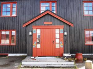 a black house with a red door and windows at Basecamp Frich`s Hjerkinn in Hjerkinn +89 photos