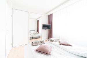 ein weißes Zimmer mit 2 Betten und einem Spiegel in der Unterkunft Apartman Skenderija in Sarajevo
