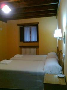 Un dormitorio con una gran cama blanca y una ventana en Apartamentos rurales La Lastra 2 llaves, en Caso