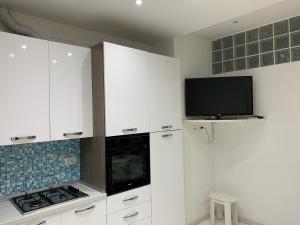 a white kitchen with a stove and a tv at Appartamento Regonini in Alassio