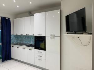 a kitchen with white cabinets and a flat screen tv at Appartamento Regonini in Alassio