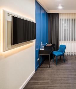 um quarto com uma televisão e uma parede azul em Hotel Rafael Готель Рафаель em Lviv