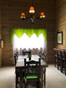 comedor con mesa y cortina verde en Cabañas Filadelfia, en Santa Rosa de Cabal