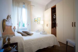 een slaapkamer met een bed met witte lakens en een raam bij L'Albero di Garibaldi in Florence