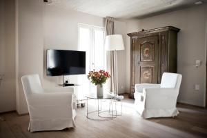 ein Wohnzimmer mit 2 weißen Stühlen und einem TV in der Unterkunft Le Coq Chantant Studios d'Hôtes & Boutique Hôtel St-Livres in Saint-Livres