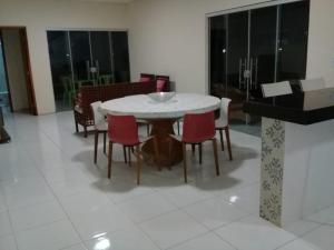 a dining room with a white table and red chairs at Casa Praia Luís Correia in Luis Correia
