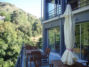 eine Terrasse mit einem Sonnenschirm, Tischen und Stühlen in der Unterkunft Ayios Andronikos Agrotourism House in Kalopanagiotis