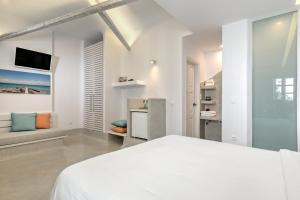a white bedroom with a bed and a tv at Kouros Village Hotel - Adults Only in Perissa